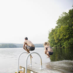 USA, New York, Putnam Valley, Roaring Brook Lake, Pärchen springt vom Steg in den See - TETF01271