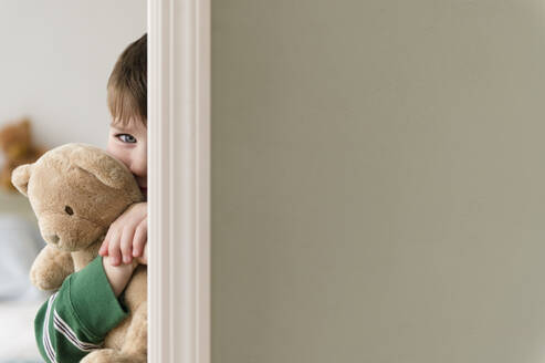 Portrait of boy (4-5) hiding behind wall - TETF01278