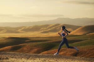 Frau joggt in Landschaft bei Sonnenuntergang - TETF01296