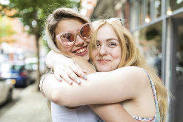 Glückliche Teenager-Mädchen mit blondem Haar, die sich gegenseitig umarmen - WPEF05827