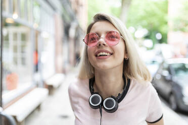 Cheerful teenager with wireless headphones wearing sunglasses - WPEF05833