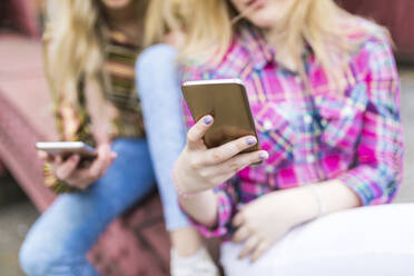 Teenage girls text messaging through smart phones - WPEF05844