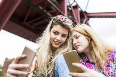 Lächelnder Teenager, der ein Selfie mit einem Freund über ein Mobiltelefon macht - WPEF05845