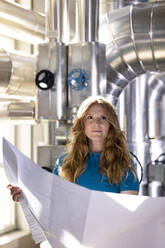 Blond technician holding blueprint in industry - FKF04663