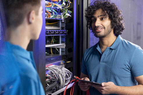 IT-Techniker bespricht sich mit einem Auszubildenden im Serverraum in der Industrie - FKF04664