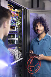 IT support discussing with trainee in server room at industry - FKF04665