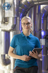 Lächelnder Techniker mit Brille und Tablet-PC in einer Fabrik - FKF04716