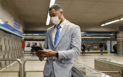 Geschäftsmann mit Gesichtsschutz und Tablet-PC am Bahnhof - JCCMF05666