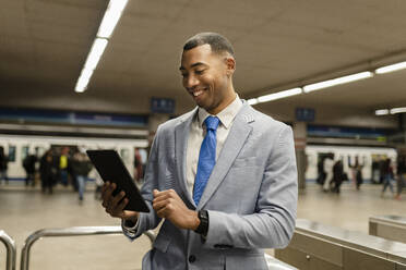 Glücklicher Geschäftsmann mit Tablet-PC am Bahnhof - JCCMF05667