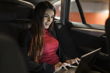 Geschäftsfrau benutzt Laptop im Auto bei Nacht - JRVF02865
