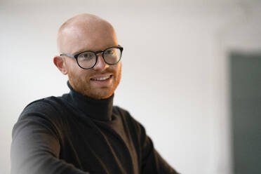 Smiling bald working man wearing eyeglasses in office - JOSEF07594