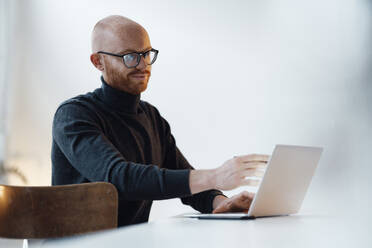 Junger Geschäftsmann mit Laptop bei der Arbeit im Büro - JOSEF07619