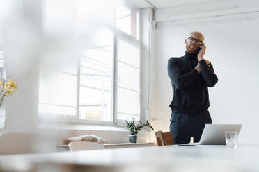 Young business man talking on mobile phone in office - JOSEF07646