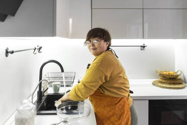 Ältere Frau wäscht Geschirr in der Küche zu Hause - VBUF00073