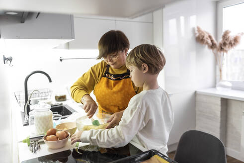 Großmutter mit Enkel beim Kochen in der Küche zu Hause - VBUF00075