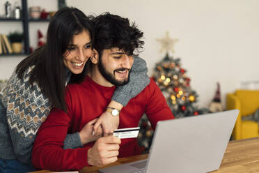 Happy couple doing online shopping using laptop at home - GIOF14933