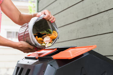 Nahaufnahme einer Frau, die Küchenabfälle in die Komposttonne gibt - TETF01350