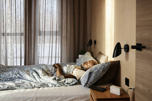 Mann schläft auf gemütlichem Bett am Morgen zu Hause - DSHF00135