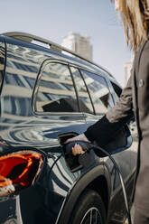 Porträt einer Frau mit Schutzmaske, die ihren Einkaufskorb in den  Kofferraum ihres Autos stellt, lizenzfreies Stockfoto