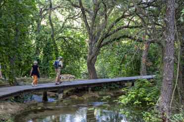 Senior couple walking on footbridge with dog at vacation, Krka National Park, Sibenik-Knin, Croatia - MAMF02032