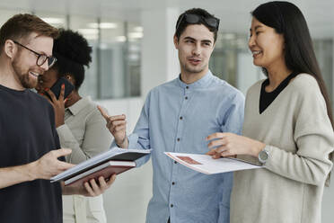 Happy business colleagues discussing with each other standing in modern office - DSHF00231