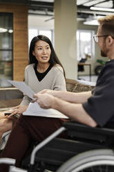 Businesswoman talking to disabled colleague in office - DSHF00238