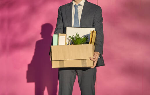 Businessman carrying box with personal belongings on sunny day - VEGF05455