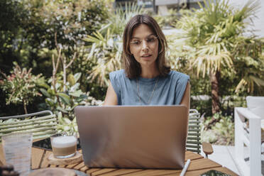 Freelancer working on laptop in back yard - MFF08737