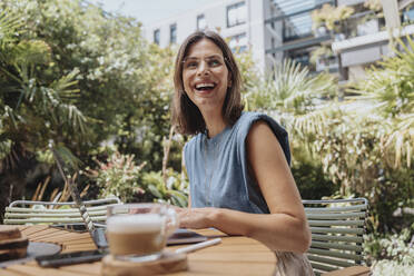 Happy businesswoman with laptop at back yard - MFF08741