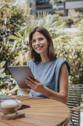 Smiling businesswoman with tablet computer at back yard - MFF08743