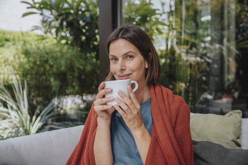 Lächelnde Frau mit Kaffeetasse im Hinterhof - MFF08762