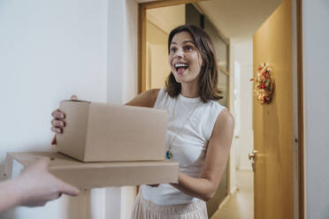 Überraschte Frau, die Pakete von einem Zusteller an der Tür erhält - MFF08797