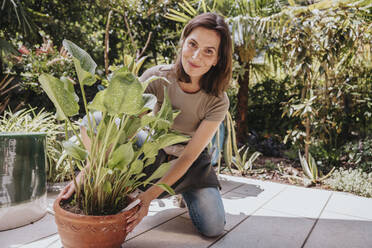 Smiling gardener holding potted plant in garden - MFF08816