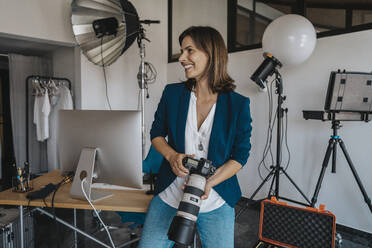 Lächelnder Fotograf mit Kamera im Studio - MFF08849