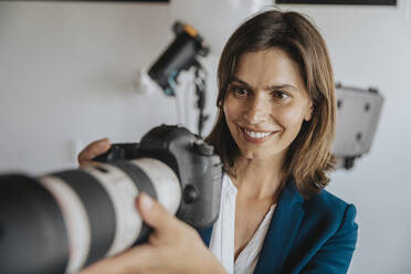 Überraschungsfotograf mit Blick auf die Digitalkamera im Studio - MFF08853