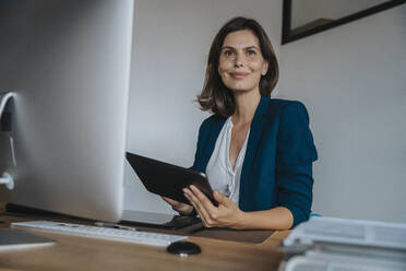 Nachdenklicher Fotograf mit Tablet-PC am Schreibtisch im Studio - MFF08857