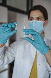 Doctor holding vial and syringe in clinic - MFF08887