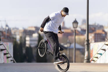 Entschlossener Mann macht Wheelie auf dem Fahrrad in der Stadt - OCMF02343