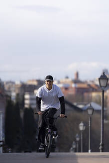 Man riding bicycle on street in city - OCMF02344