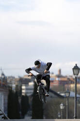 Man doing trick on bicycle in city at weekend - OCMF02345