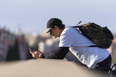 Mann mit Smartphone an der Wand lehnend - OCMF02348