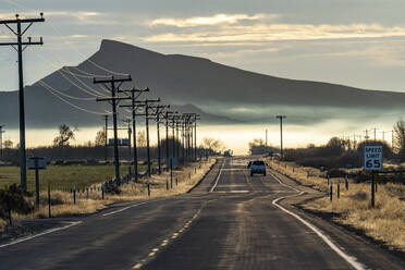 USA, Idaho, Bellevue, Ländliche Straße mit Berg und Morgennebel in der Ferne - TETF01382