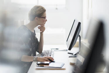 Side view of business woman working on desktop pc in office - TETF01414