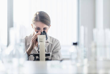 Laborantin bei der Analyse einer Probe durch ein Mikroskop - TETF01419