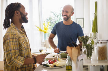 Lächelndes homosexuelles Paar trinkt Wein in der Küche - TETF01440