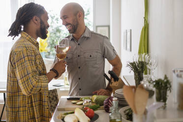Lächelndes homosexuelles Paar trinkt Wein in der Küche - TETF01441