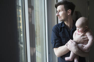 Father looking through window with daughter (2-5 months) - TETF01448