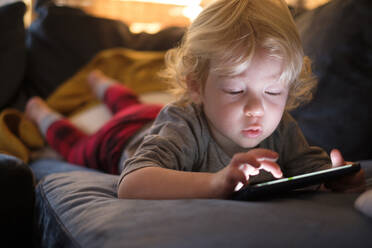 Kleiner Junge (2-3) liegt auf der Vorderseite und spielt ein Spiel auf dem Smartphone - TETF01465