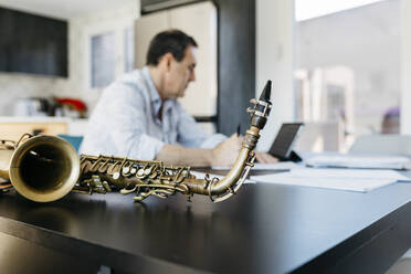 Saxophon wird von einem am Tisch sitzenden Musiker gehalten - JRFF05313