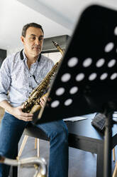 Saxophonist mit Saxophon auf dem Tisch zu Hause - JRFF05320